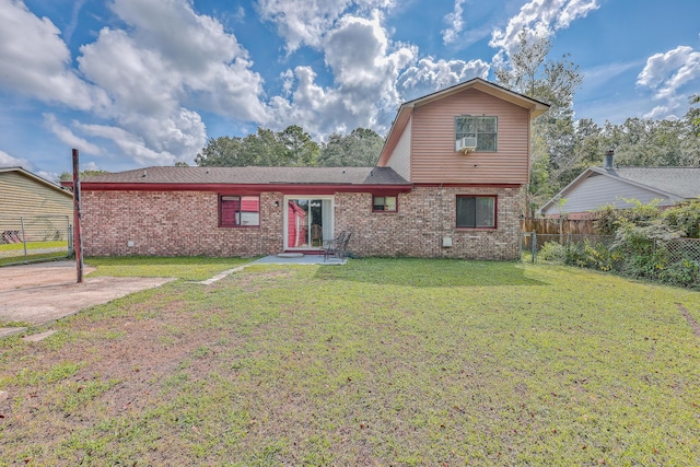 view of front of home with brick siding, a patio area, a front lawn, and fence