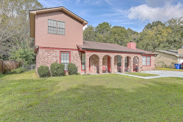 view of front of home with brick siding, a chimney, a front lawn, and fence