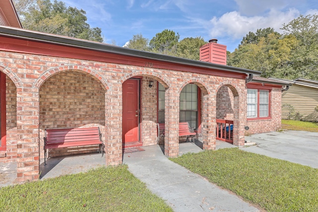 exterior space with a patio, brick siding, and a chimney