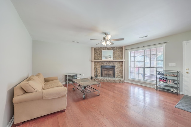 living area featuring ceiling fan, baseboards, wood finished floors, and a fireplace