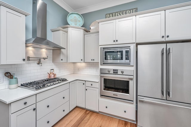 225 Camber Rd, Huger, SC 29450 - kitchen featuring stainless steel appliances, wall chimney exhaust hood, light countertops, decorative backsplash, and light wood-style floors