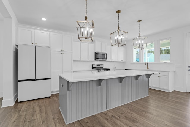 1238 Homecoming Blvd, Ravenel, SC 29470 - kitchen with a kitchen island, wood finished floors, white cabinets, appliances with stainless steel finishes, and a chandelier