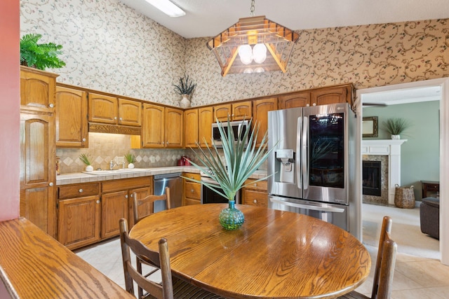 kitchen featuring hanging light fixtures, a high end fireplace, stainless steel appliances, and light tile patterned flooring