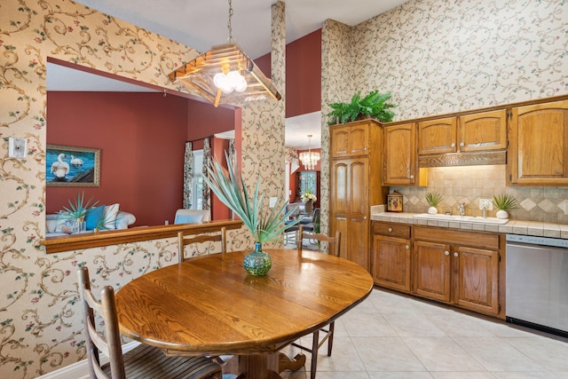 kitchen featuring light tile patterned flooring, sink, decorative light fixtures, tile counters, and dishwasher