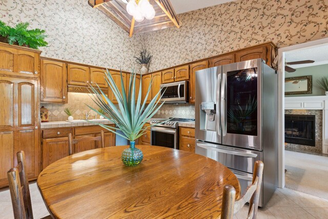 kitchen featuring light tile patterned flooring, ceiling fan, stainless steel appliances, and a premium fireplace