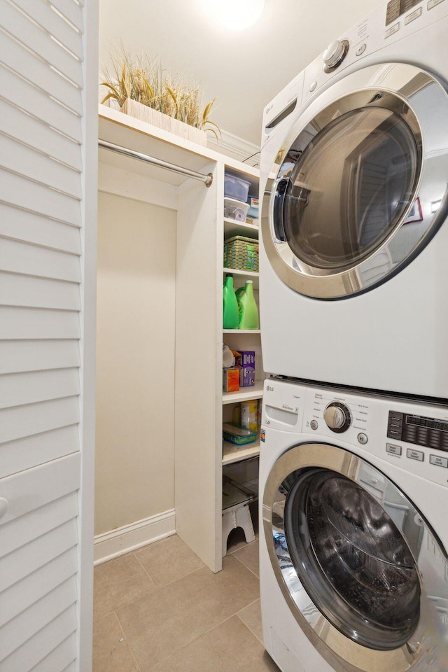 washroom with stacked washer / drying machine and light tile patterned floors