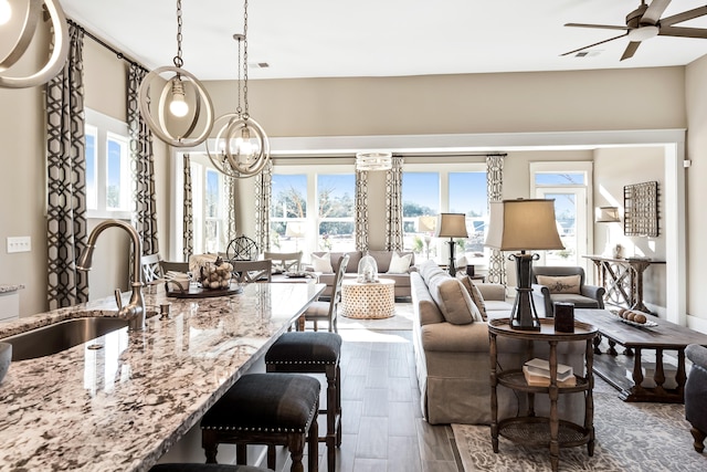 kitchen featuring a breakfast bar area, sink, hanging light fixtures, ceiling fan with notable chandelier, and dark hardwood / wood-style flooring