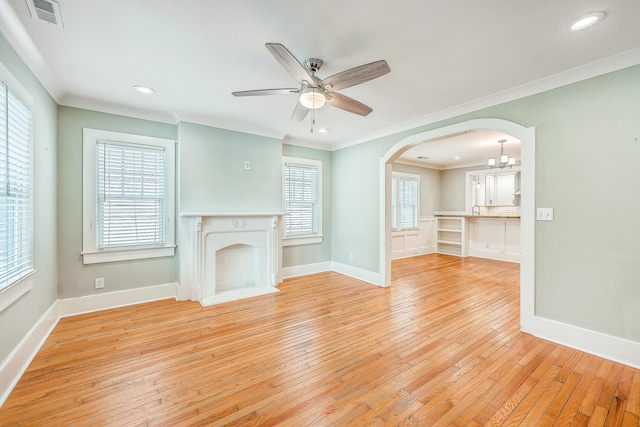 unfurnished living room featuring arched walkways, light wood finished floors, visible vents, and crown molding