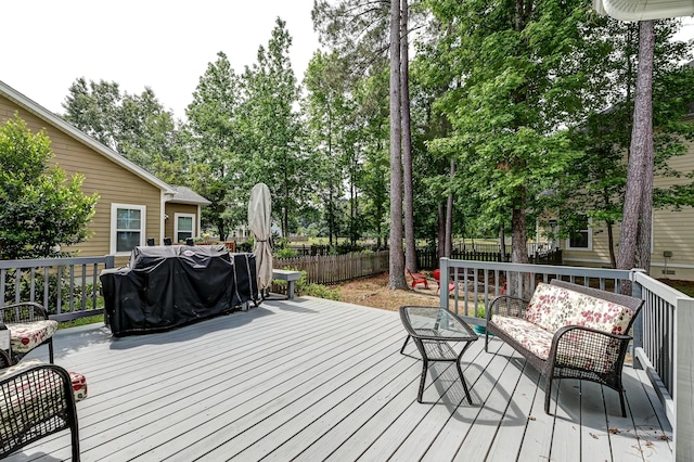 wooden terrace featuring a fenced backyard, an outdoor living space, and view of scattered trees