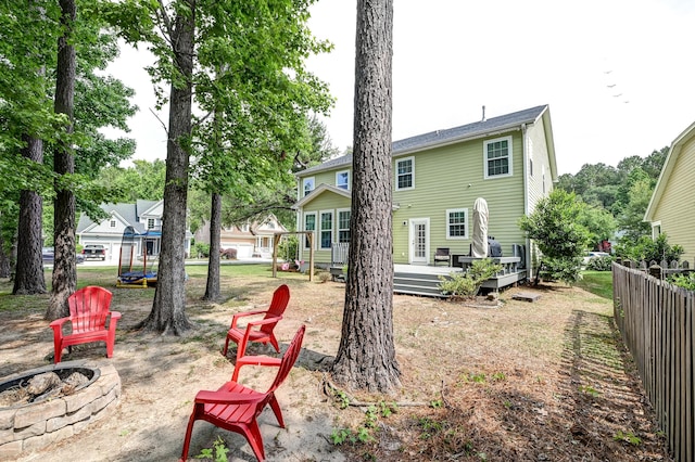 back of house with an outdoor fire pit, a deck, and fence