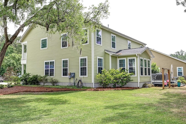 back of property with a yard and a wooden deck
