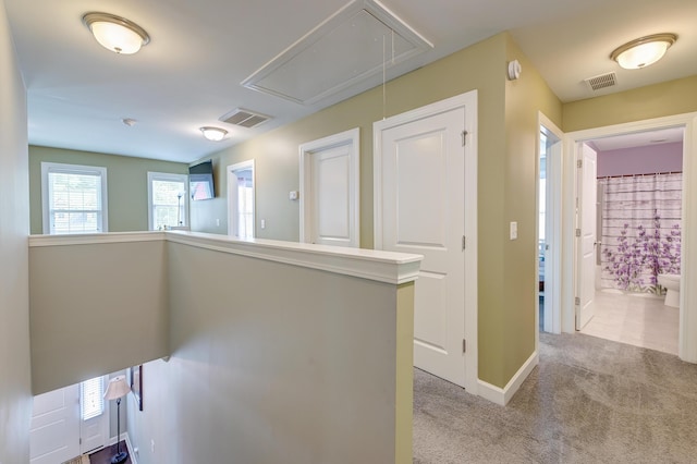 corridor featuring attic access, carpet, and baseboards