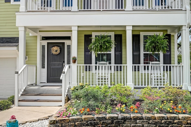 property entrance featuring a balcony, a garage, and a porch