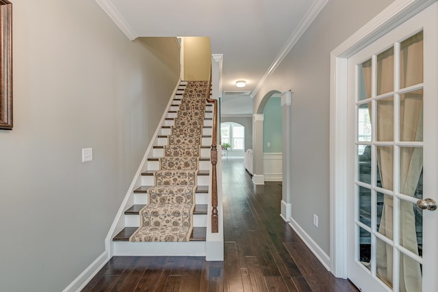 stairs featuring arched walkways, crown molding, hardwood / wood-style flooring, and baseboards