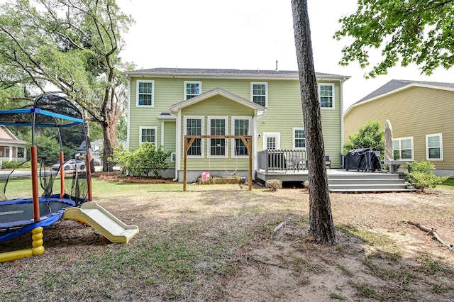 rear view of property with a trampoline and a deck