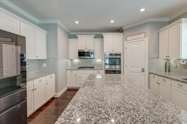 kitchen with stainless steel appliances, white cabinetry, ornamental molding, decorative backsplash, and dark wood finished floors