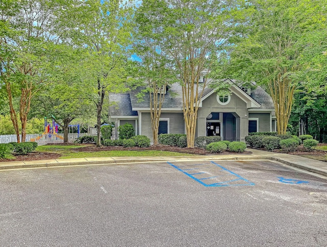 view of front of house featuring uncovered parking, fence, and roof with shingles