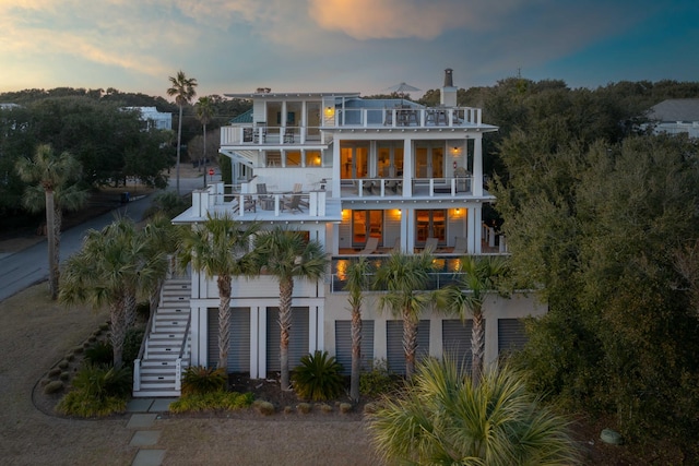 4001 Palm Blvd, Isle Of Palms, SC 29451 - back of house at dusk featuring a balcony, stairs, and a chimney