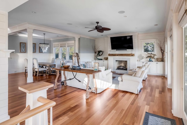 4001 Palm Blvd, Isle Of Palms, SC 29451 - living area featuring a fireplace, ornate columns, a ceiling fan, light wood-type flooring, and a wainscoted wall