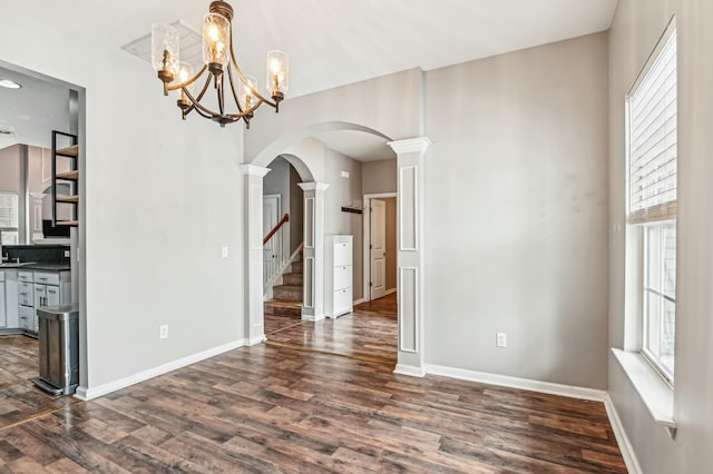 unfurnished dining area featuring dark hardwood / wood-style floors and ornate columns