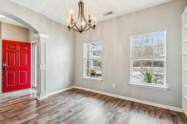 foyer featuring decorative columns, a healthy amount of sunlight, and dark hardwood / wood-style flooring