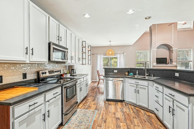 kitchen featuring sink, white cabinetry, hardwood / wood-style floors, hanging light fixtures, and stainless steel appliances