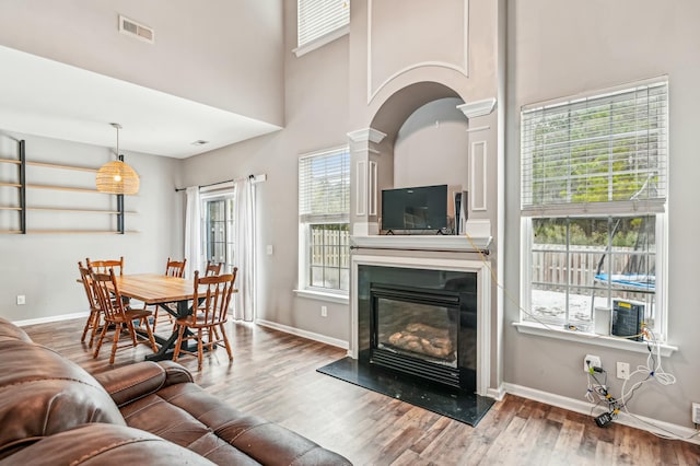 living room featuring hardwood / wood-style flooring, a towering ceiling, and ornate columns