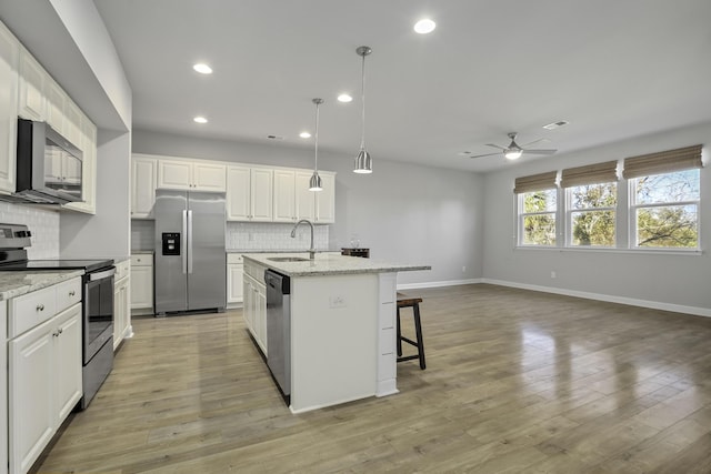 kitchen featuring white cabinetry, stainless steel appliances, sink, a kitchen island with sink, and ceiling fan