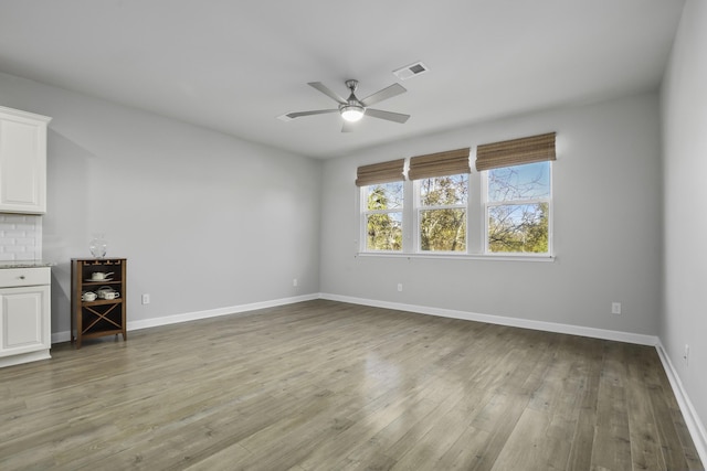 empty room with ceiling fan and hardwood / wood-style flooring