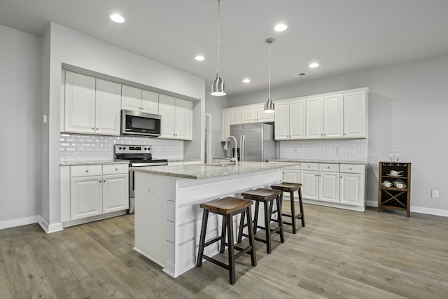 kitchen with white cabinets, appliances with stainless steel finishes, and a center island with sink