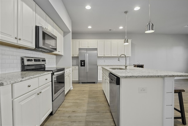 kitchen with white cabinetry, appliances with stainless steel finishes, and an island with sink