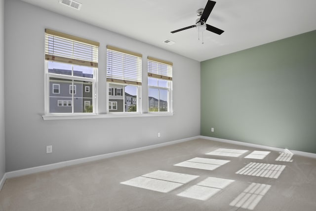 unfurnished room with ceiling fan, a wealth of natural light, and light carpet