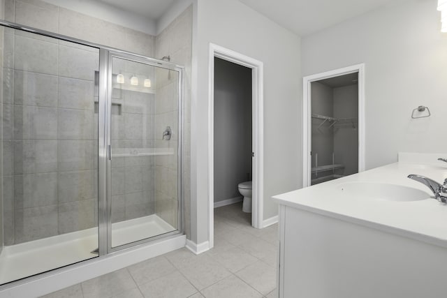 bathroom featuring toilet, tile patterned floors, a shower with shower door, and vanity