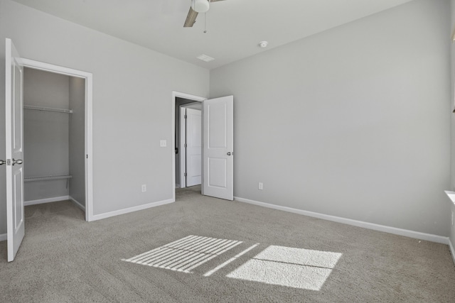 unfurnished bedroom featuring ceiling fan, a closet, a spacious closet, and carpet flooring