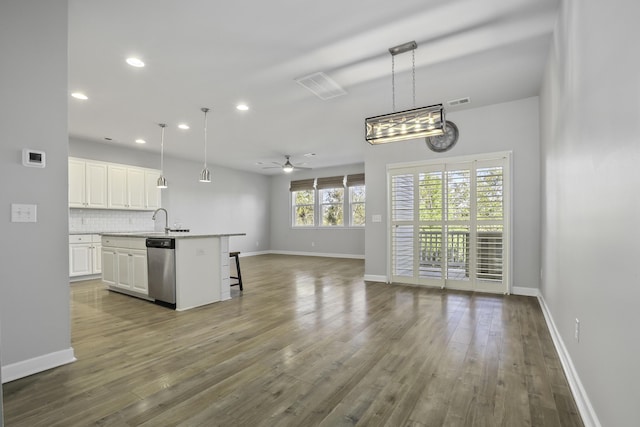 kitchen featuring white cabinetry, stainless steel dishwasher, hanging light fixtures, and an island with sink