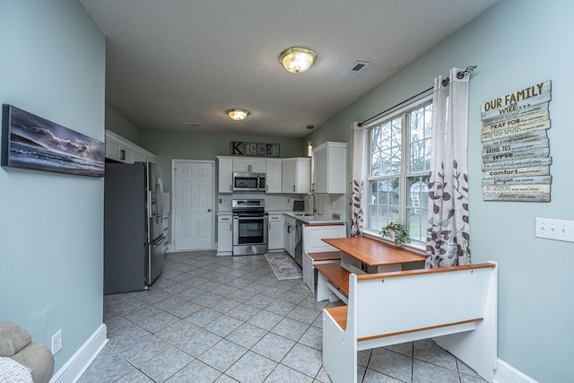 kitchen featuring visible vents, a sink, white cabinetry, appliances with stainless steel finishes, and light countertops