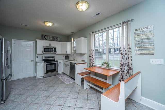 kitchen with visible vents, light countertops, stainless steel appliances, white cabinetry, and a sink