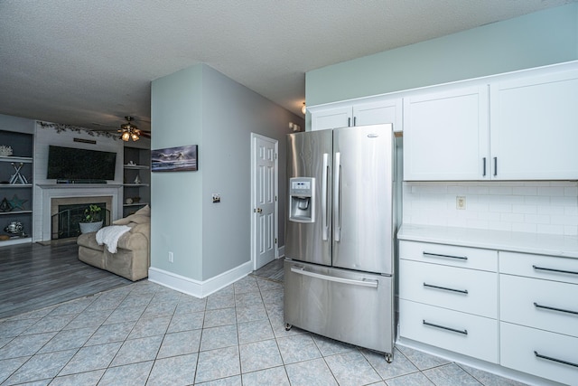 kitchen featuring a ceiling fan, light tile patterned flooring, white cabinets, stainless steel refrigerator with ice dispenser, and a textured ceiling