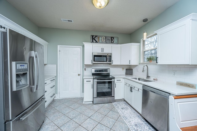 kitchen with a sink, stainless steel appliances, white cabinetry, and light countertops