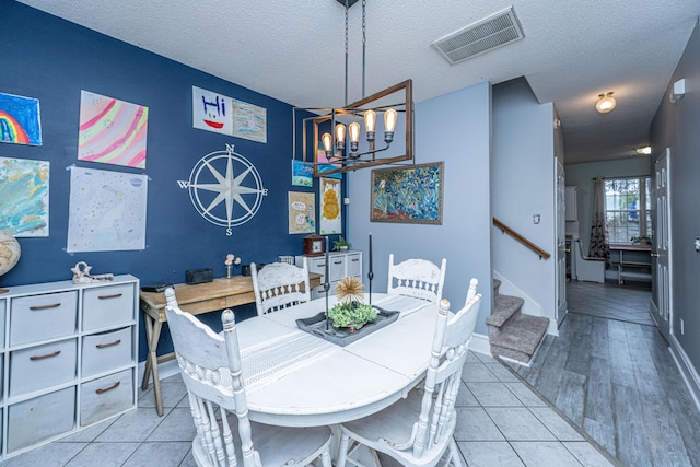 dining area featuring visible vents, a chandelier, stairway, light wood-type flooring, and a textured ceiling