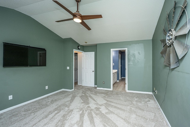 unfurnished bedroom featuring ensuite bath, lofted ceiling, baseboards, and light carpet