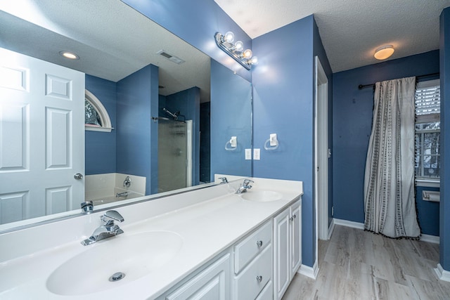 full bathroom with a sink, visible vents, a textured ceiling, and walk in shower