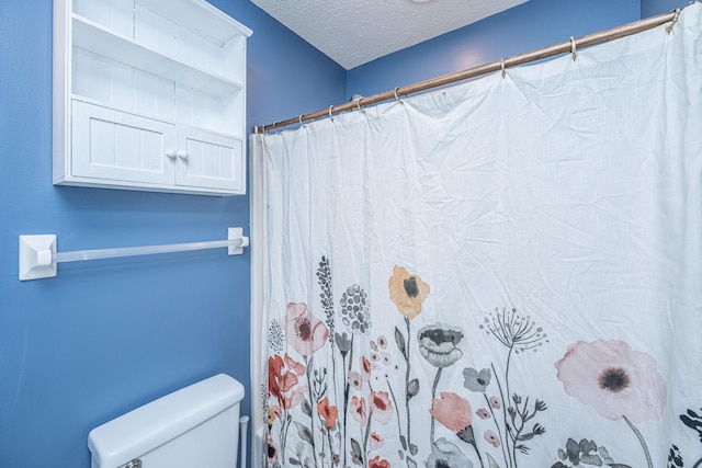 bathroom with toilet, a textured ceiling, and a shower with shower curtain