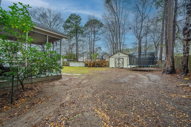 view of yard featuring a storage shed, a trampoline, fence, and an outdoor structure