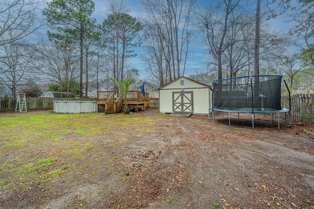 view of yard with a fenced backyard, a trampoline, an outdoor structure, and a shed