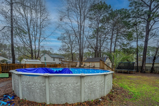 view of pool featuring a trampoline, a fenced backyard, a fenced in pool, and a lawn