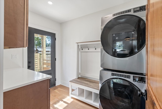 clothes washing area featuring light hardwood / wood-style flooring and stacked washing maching and dryer