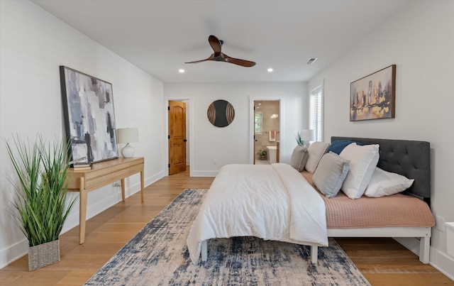 bedroom with ensuite bathroom, light hardwood / wood-style floors, and ceiling fan