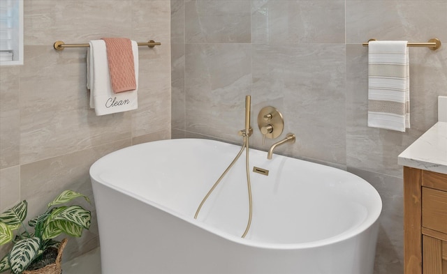 bathroom with tile walls, vanity, and a bathtub