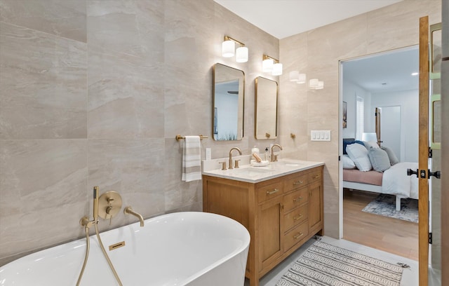 bathroom with vanity, tile walls, and a bathing tub